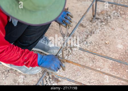 I lavoratori utilizzano pinze, legare il filo alla fondazione per armature da utilizzare come base per travasare il calcestruzzo. Foto Stock