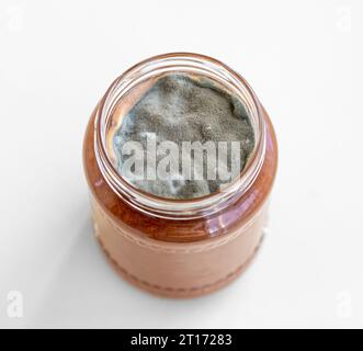 Aprire il vaso con marmellata dolce e muffa su sfondo bianco. Foto Stock