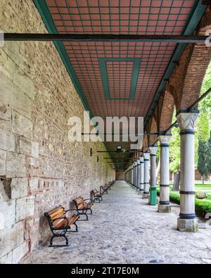 Passerella pavimentata coperta lunga con colonne e panche. Il passaggio pedonale si trova nel cortile del Palazzo Topkapi, un ex palazzo reale a Istanbul, Turchia Foto Stock