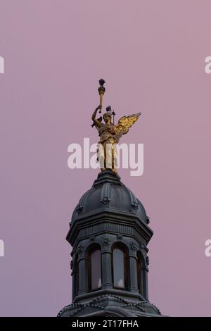 Un angelo d'oro sulla cupola della biblioteca pubblica Gradska knjižnica nel centro di Zagabria, di fronte alla stazione ferroviaria durante un'alba colorata Foto Stock