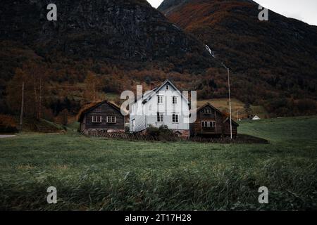 Una vista panoramica di piccole case in legno annidate in una valle erbosa circondata da torreggianti montagne Foto Stock
