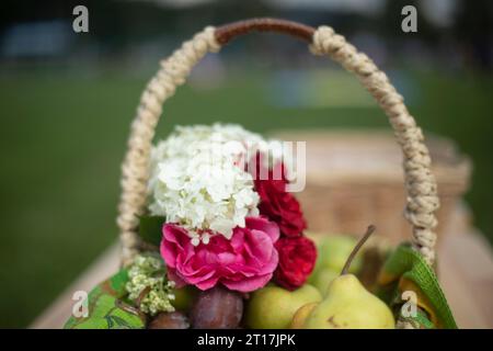 Cestino con fiori. Fiori e frutta. Cestino di vimini. Fiori in giardino. Foto Stock