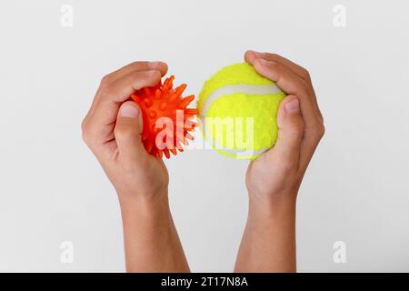 Palla ad ago con massaggio arancione e palla da tennis gialla nelle mani dei bambini Foto Stock