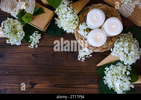 Ci sono candele accese, regali e fiori su un tavolo di legno scuro. Foto di alta qualità Foto Stock