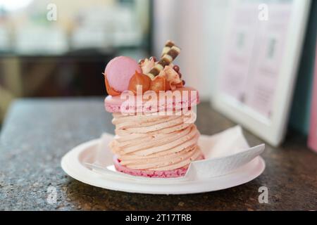 Macaroon. Delizioso dessert francese rosa con decorazioni gustose. Macaron con formaggio spalmabile sul tavolo nel caffè Foto Stock