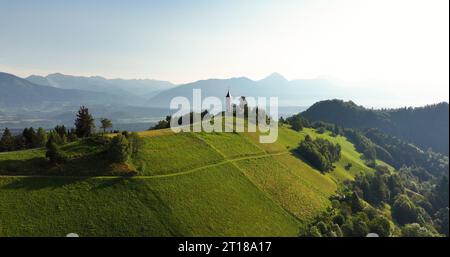 Vista aerea mattutina di St Chiesa di Primoz a Jamnik, Slovenia, alpi Giulie Foto Stock