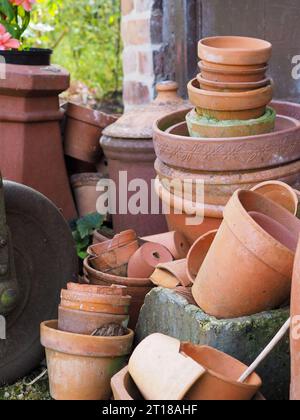 Pile di vecchie pentole in terracotta d'epoca e pentole rotte per crocks in un cottage-giardino britannico - uno spazio perfetto per svernare per insetti e animali selvatici Foto Stock