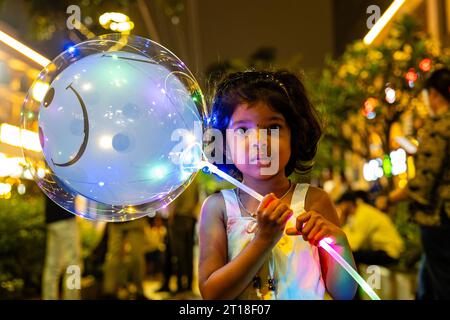 Un bambino tiene in mano una mongolfiera per strada Foto Stock