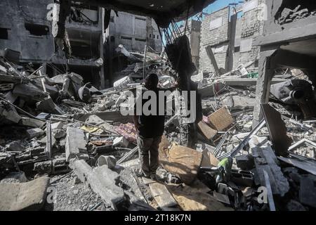 Gaza City, territori palestinesi. 12 ottobre 2023. Un uomo palestinese si trova tra le macerie di edifici distrutti dagli attacchi aerei israeliani nel campo profughi di al-Shati nella città di Gaza, mentre i combattimenti tra Israele e Hamas continuano per il sesto giorno. Credito: Mohammed Talatene/dpa/Alamy Live News Foto Stock