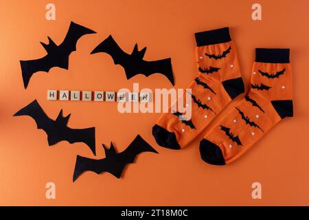 Calzini arancioni con pipistrelli. Costume di abbigliamento per la festa di Halloween. Vista dall'alto della calza vivace e multicolore. Frase in lettere di legno. Parola. Foto Stock