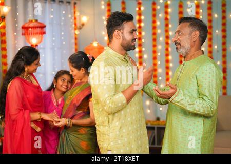 Un figlio felice con la nuora e i bambini sono venuti per la celebrazione del festival diwali a casa dei nonni - concetto di riunione di famiglia, legame con le relazioni Foto Stock