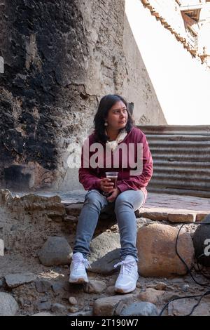 La Paz, Bolivia - 8 agosto 2022: Donna boliviana seduta su Bleachers che beve una bevanda calda da una tazza di plastica Foto Stock