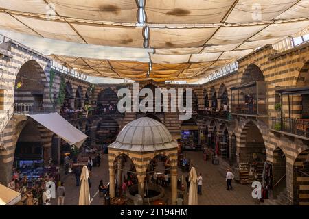 DIYARBAKIR, TURCHIA, 5 OTTOBRE 2023: Veduta di Hasanpasa Khan, edificio storico medievale dove la gente fa colazione e piccoli negozi, il centro Foto Stock