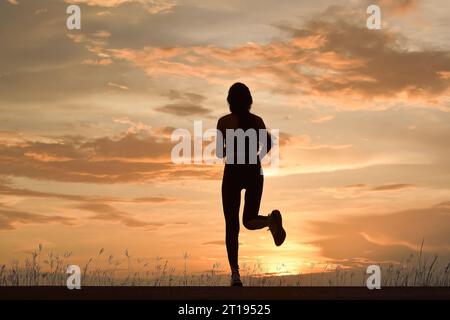 Vista posteriore di una donna che corre al tramonto, Thailandia Foto Stock
