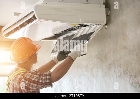 Elettricista che installa un'unità di climatizzazione su una parete, Thailandia Foto Stock