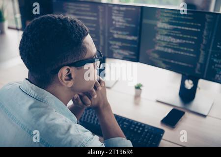 Foto posteriore di un nerd geek che pensa di riparare il suo bug sul monitor del computer il programmatore javascript si trova all'interno dell'area di lavoro dell'ufficio Foto Stock