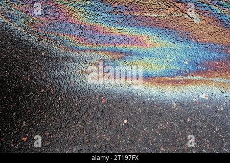 Macchie di olio o benzina sono sparse casualmente sull'asfalto dopo la pioggia. Primo piano di sfondo astratto Foto Stock