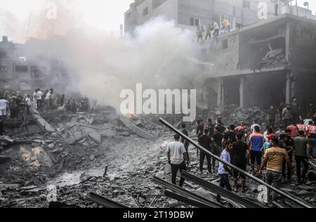 Rafah, territori palestinesi. 12 ottobre 2023. La gente spegne un incendio nel sito degli attacchi aerei israeliani mentre continuano i combattimenti tra le truppe israeliane e i militanti islamici di Hamas. Crediti: Abed Rahim Khatib/dpa/Alamy Live News Foto Stock