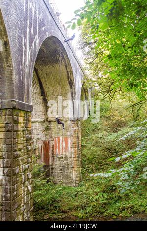 Uomo in discesa da un viadotto ferroviario in disuso sul Monsal Trail, l'ex linea ferroviaria Manchester-Londra nel Derbyshire Peak District in Inghilterra Foto Stock