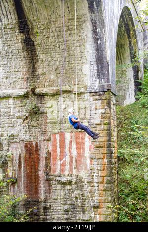 Uomo in discesa da un viadotto ferroviario in disuso sul Monsal Trail, l'ex linea ferroviaria Manchester-Londra nel Derbyshire Peak District in Inghilterra Foto Stock