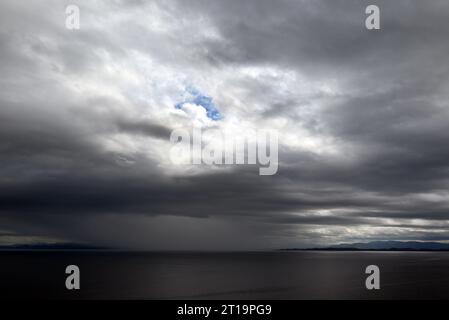 Una tempesta che si avvicina con nuvole nere sulla costa delle isole di Skye, in Scozia. Un foro blu attraverso le nuvole è ancora visibile. Foto Stock