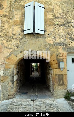 Un vicolo incastonato tra le mura della città bastide di Monpazier, nella regione francese della Dordogna. La città è una popolare destinazione turistica. Foto Stock