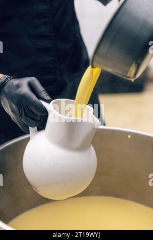 Il brodo di pollo viene versato nella brocca da portata nella cucina del ristorante Foto Stock