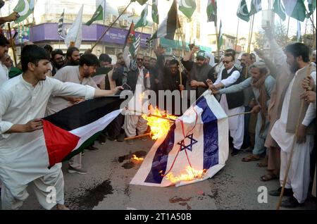 HYDERABAD, PAKISTAN, 12/10/2023, i membri del Balochistan di Anjuman-e-Tajran bruciano la bandiera israeliana mentre stanno tenendo una manifestazione di protesta contro l'aggressione e le atrocità israeliane sulla Striscia di Gaza e solidarietà con i palestinesi, al press club Quetta giovedì 12 ottobre 2023. Foto Stock