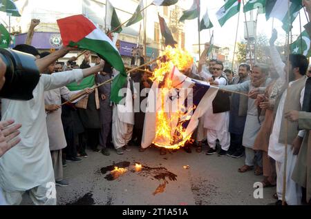 HYDERABAD, PAKISTAN, 12/10/2023, i membri del Balochistan di Anjuman-e-Tajran bruciano la bandiera israeliana mentre stanno tenendo una manifestazione di protesta contro l'aggressione e le atrocità israeliane sulla Striscia di Gaza e solidarietà con i palestinesi, al press club Quetta giovedì 12 ottobre 2023. Foto Stock