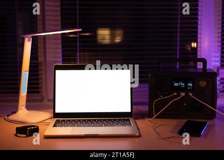 Stazione di ricarica per laptop e lampada da scrivania quando non c'è luce durante il blackout. Batteria del gruppo di alimentazione del generatore in assenza di elettricità. a casa Foto Stock