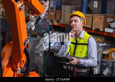 La riparazione del servizio di lavoro maschile per caucasione ingegneristica aziona il braccio di saldatura robotizzato automatico con il pensiero di domande che risolve l'espressione del problema Foto Stock