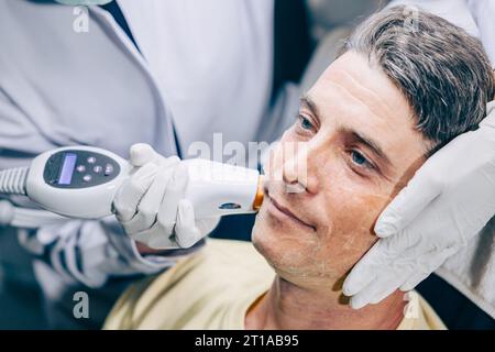 Medico della pelle che utilizza la tecnologia di trattamento viso viso con trattamento laser risurfacing con maschio adulto per ridurre rughe e cicatrici presso la clinica anti invecchiamento Foto Stock