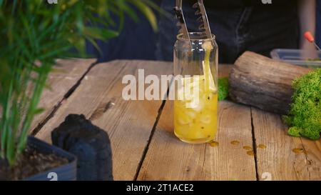 Primo piano per un cocktail freddo estivo. Cocktail con frutto della passione, mango e cubetti di ghiaccio in un bicchiere. Cocktail tradizionale italiano. Il processo di maki Foto Stock