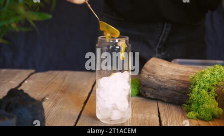 Primo piano per un cocktail freddo estivo. Cocktail con frutto della passione, mango e cubetti di ghiaccio in un bicchiere. Cocktail tradizionale italiano. Il processo di maki Foto Stock