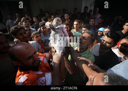 I palestinesi tengono il cadavere di un bambino ucciso nell'attacco al campo profughi di al-Shati mentre le operazioni di ricerca e salvataggio continuano a Gaza i palestinesi tengono il cadavere di un bambino ucciso nell'attacco al campo profughi di al-Shati mentre le operazioni di ricerca e salvataggio continuano a Gaza City On 12 ottobre 2023. Foto di Majdi Fathi apaimages Gaza città Striscia di Gaza territorio palestinese 121023 Gaza MF 2 007 Copyright: XapaimagesxMajdixFathixxapaimagesx credito: Imago/Alamy Live News Foto Stock