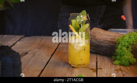 Primo piano per un cocktail freddo estivo. Cocktail con frutto della passione, mango e cubetti di ghiaccio in un bicchiere. Cocktail tradizionale italiano. Il processo di maki Foto Stock