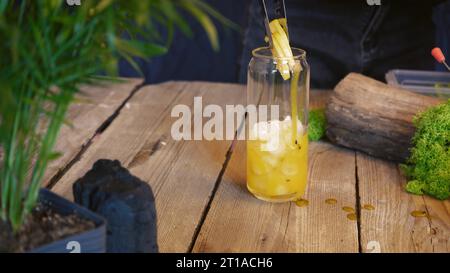 Primo piano per un cocktail freddo estivo. Cocktail con frutto della passione, mango e cubetti di ghiaccio in un bicchiere. Cocktail tradizionale italiano. Il processo di maki Foto Stock