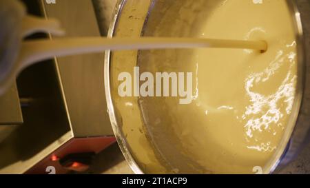 Cucinare i waffle belgi in una macchina per waffle in una caffetteria. Primo piano di uno chef che versa l'impasto per waffle in una macchina per waffle in una cucina professionale Foto Stock