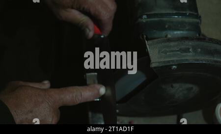 Lavori di molatura con attrezzature lisce per acciaio metallo, ferro. Primo piano delle scintille in officina. Utensili di lavorazione su una rettificatrice Foto Stock