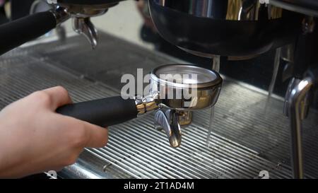 Preparazione del caffè macinato con la spolveratura di caffè fresco. Manomissione del caffè appena macinato. Il barista tiene e preme il caffè in polvere Foto Stock