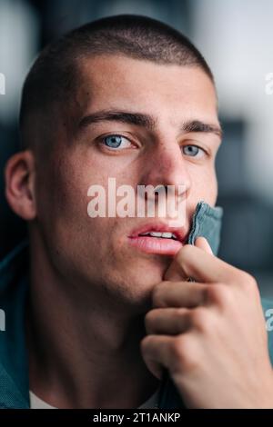 Un ritratto ravvicinato di un bel giovane con gli occhi verdi che guardano direttamente nella fotocamera Foto Stock