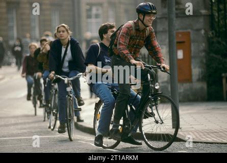 Studenti dell'Università di Oxford, il ciclismo è la principale forma di trasporto per muoversi in città. Cavalcando sul retro di una bicicletta. Oxford, Oxfordshire, Inghilterra 1990 1995 UK HOMER SYKES Foto Stock