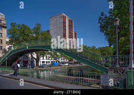 Vecchio ponte di ferro sul Canal Saint-Martin, via d'acqua costruita da Napoleone tra il 1806 e il 1825, alto edificio di appartamenti sul retro, Parigi. Francia Foto Stock