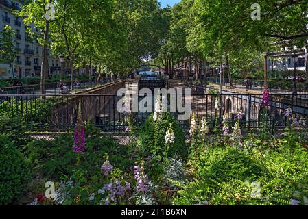 Vista del Canal Saint-Martin, canale navigabile progettato da Napoleone dal 1806 al 1825, fiori fioriti di fronte, Parigi. Francia Foto Stock