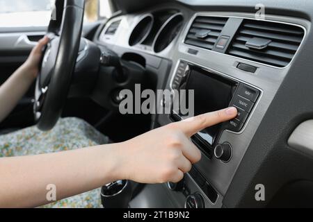 Scelta della radio preferita. Donna che preme il pulsante sull'audio del veicolo in auto, primo piano Foto Stock