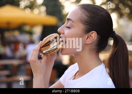 Leopoli, Ucraina - 26 settembre 2023: Donna che mangia hamburger McDonald's all'aperto Foto Stock