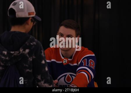 Edmonton, Alberta, Canada. 12 ottobre 2023. Edmonton Oilers ZACH HYMAN (#18) parla con un giovane tifoso mentre firma autografi al West Edmonton Mall durante un evento per iniziare la stagione 2023-2024 della NHL. (Immagine di credito: © Alexander Patton/ZUMA Press Wire) SOLO USO EDITORIALE! Non per USO commerciale! Foto Stock