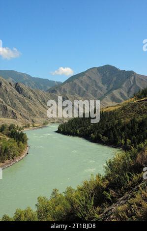 Le curve del canale di un bellissimo e ampio fiume turchese che scorre attraverso una valle deserta circondata da alte catene montuose su una limpida sommità Foto Stock