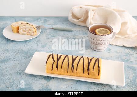 Piatti con panino dolce e una tazza di tè sul tavolo Foto Stock