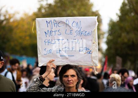 Parigi, Francia. 12 ottobre 2023. Una donna ha visto in mano un cartone che dice "Macron, ha messo la bandiera palestinese alla Torre Eiffel", durante la protesta pro-palestinese. Nonostante il ministro degli interni francese, Gérald Darmanin, che vietava tutte le proteste filo-palestinesi in Francia, diverse centinaia di persone si sono riunite a Place de la Republique, a Parigi, per dimostrare il proprio sostegno alla Palestina. La polizia ha cercato di fermare la protesta e disperdere la folla usando gas lacrimogeni e cannoni ad acqua. Credito: SOPA Images Limited/Alamy Live News Foto Stock